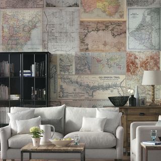 map wallpaper with living area and white sofa with cushions and book shelves