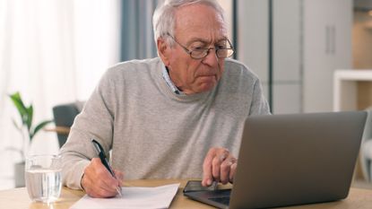 Man looking at his computer screen, holding a pen