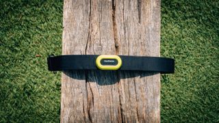 A black and yellow Garmin HRM Pro heart rate monitor wrapped around a wooden bench, with the focus on the main part of the strap
