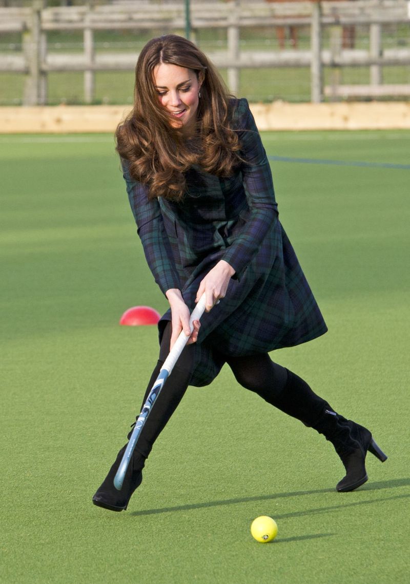 Visiting her old prep school, the Duchess dressed the part in a green tartan coat by Alexander McQueen&mdash;paired with black suede boots.
