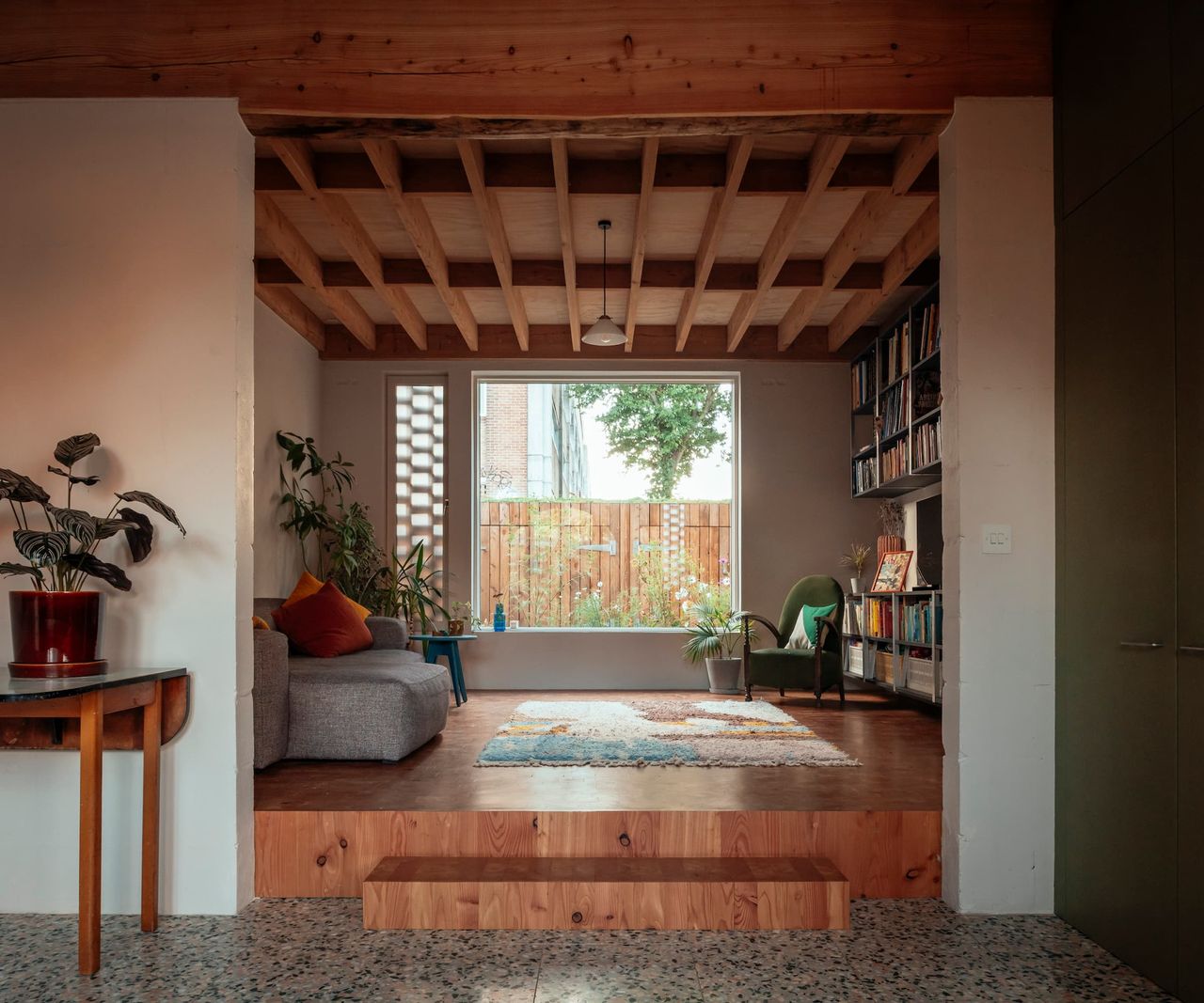 A wooden floored and ceiling in the living room with a wooden step large picture window