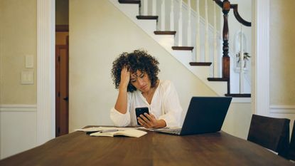 A woman sitting at a table in her home, working on her family finances