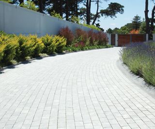 long paved driveway with low planted borders either side leading to double gates