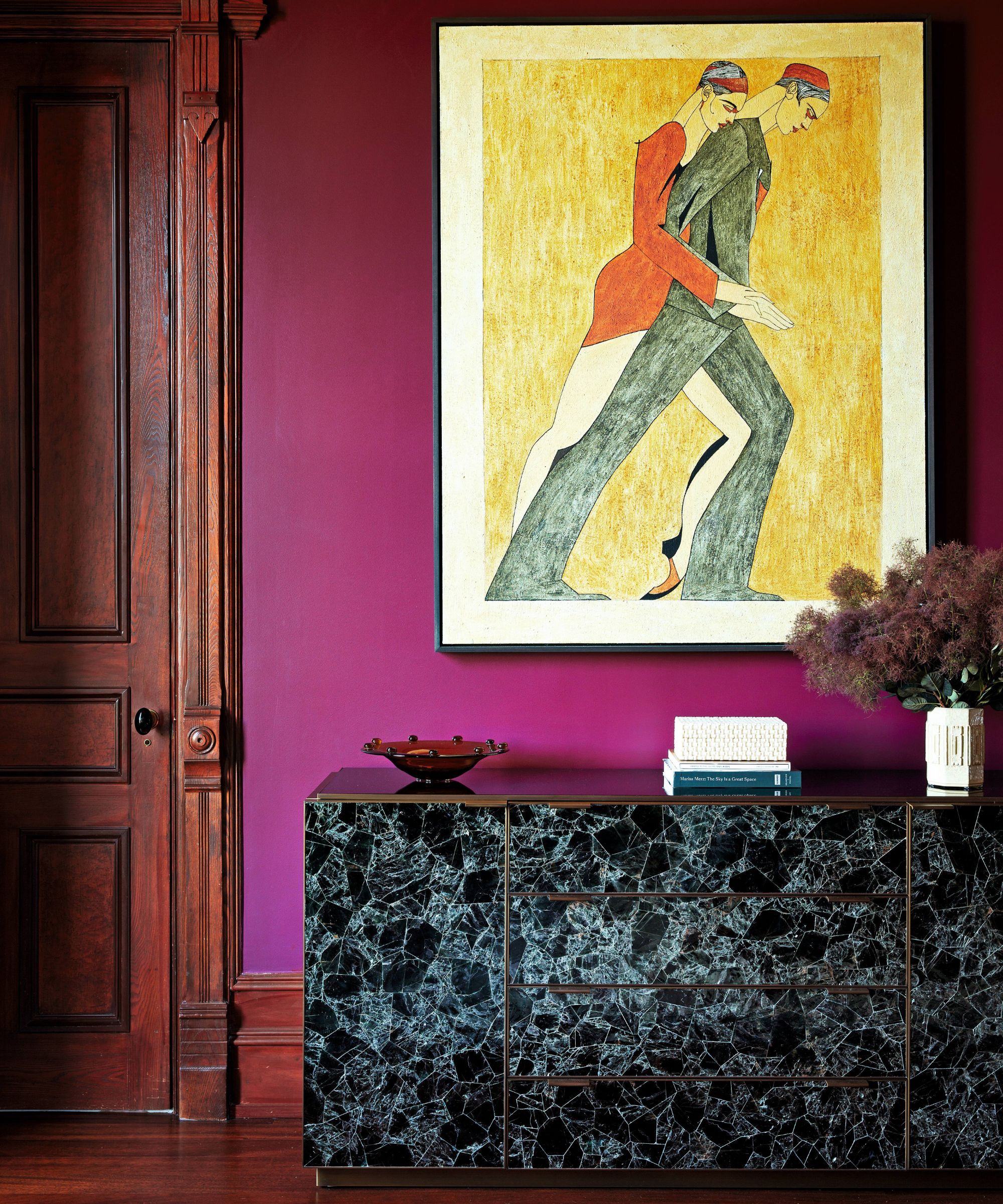 a bright pink purple bedroom with original mahogany door, large artwork and marble sideboard