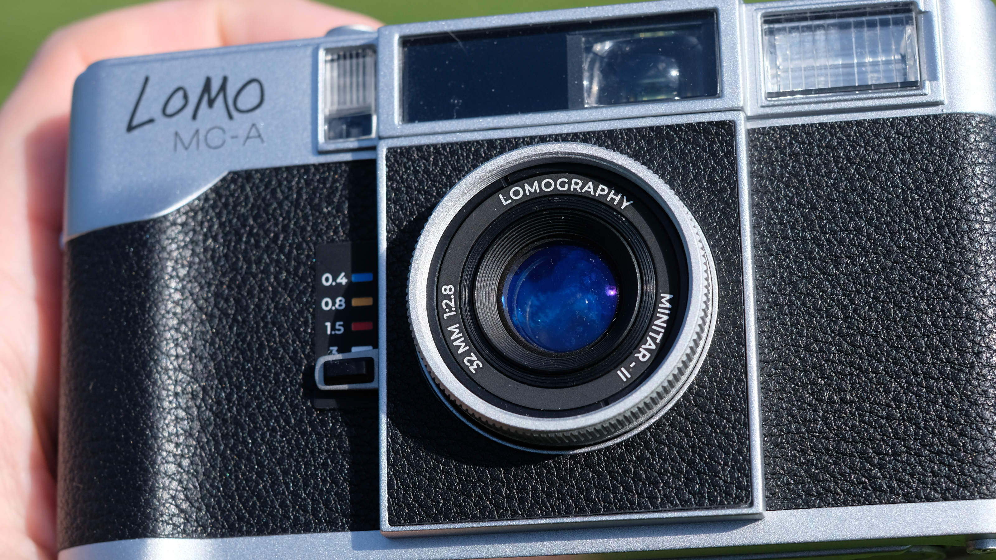 Close view of Lomography MC-A film camera, showing 32mm f/2.8 lens