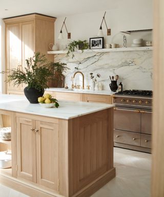 things that make a kitchen look cheap, pale wood kitchen cabinetry, marble countertops and backsplash, open shelving, brass tap
