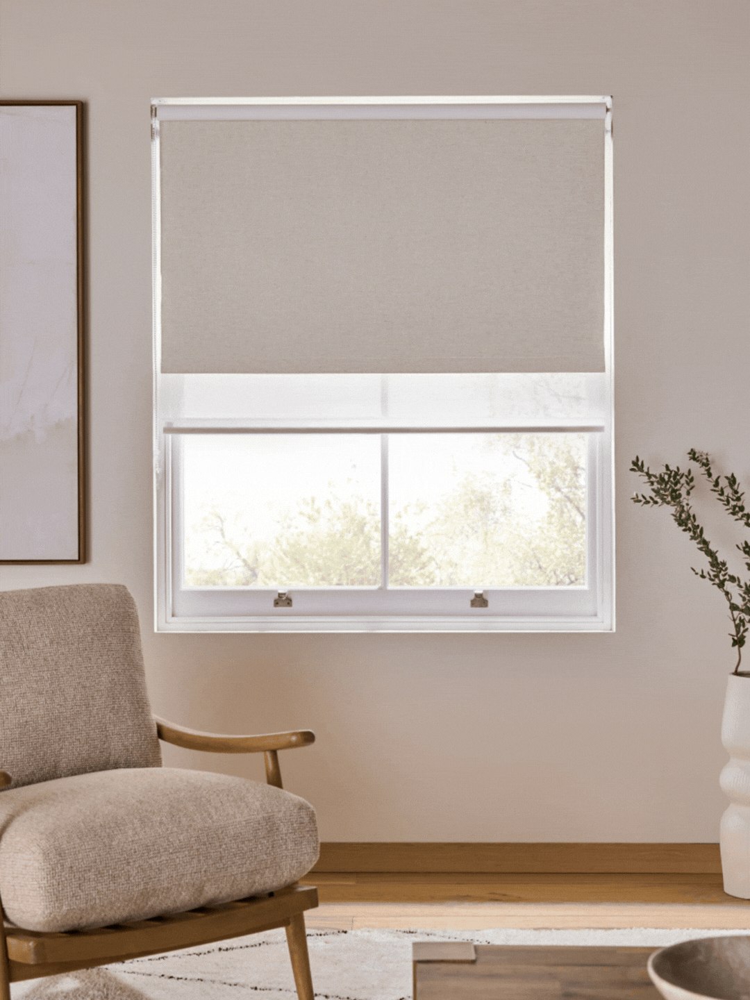 GIF of three images showing a double roller blind being pulled down on a window in a beige living room.