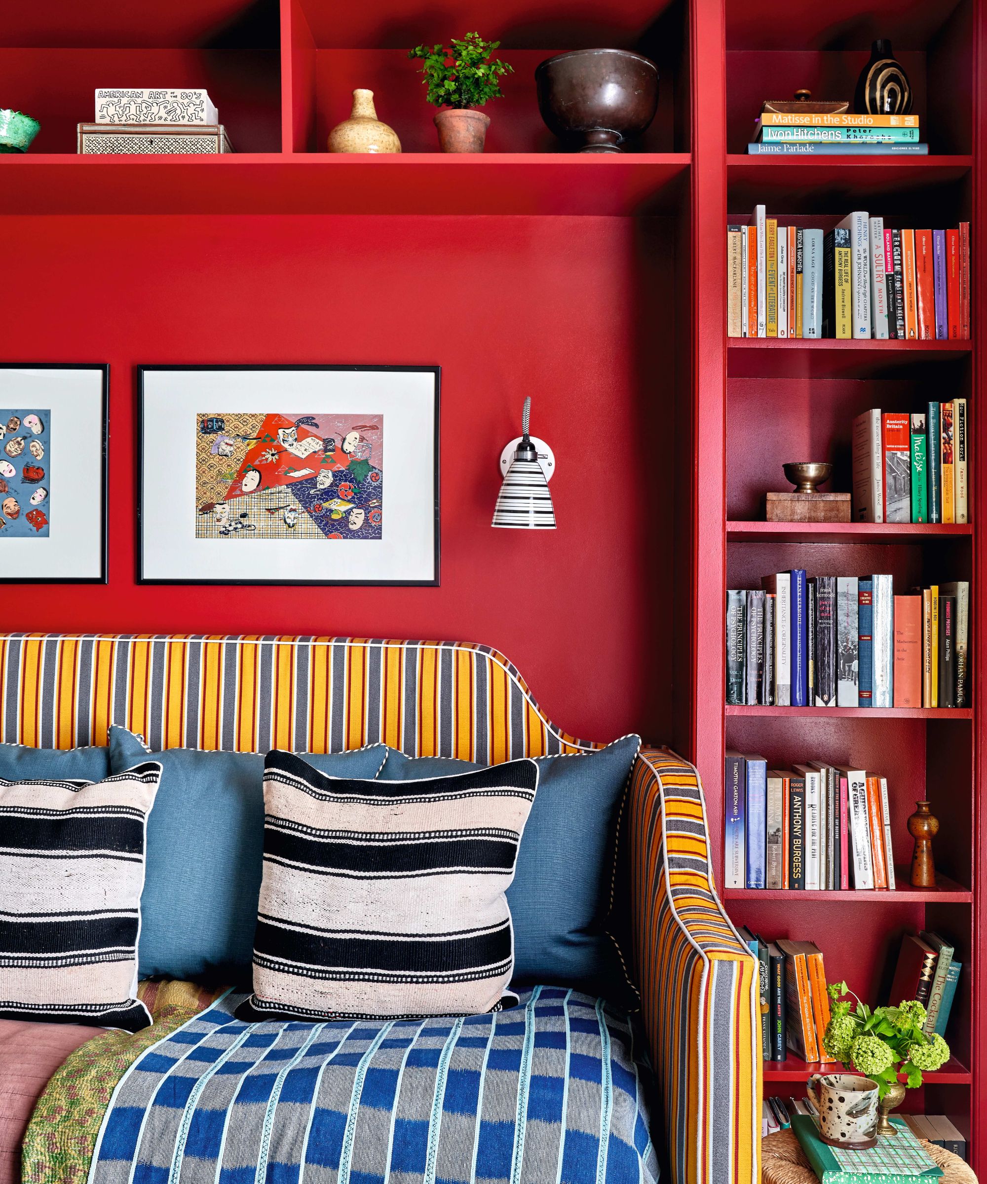 Red living room with built in storage around a yellow and blue striped sofa with black and white cushions