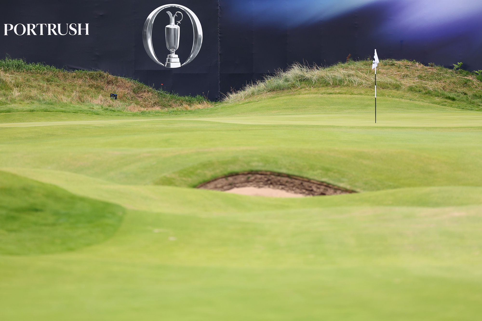 The 18th green at Royal Portrush with Open 2025 Portrush branded boarding from the grandstands surrounding it
