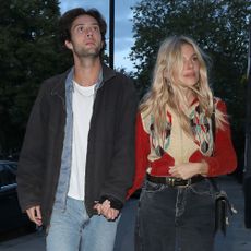 Sienna Miller styles a red cardigan and black jeans.