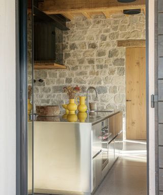 kitchen with exposed stone walls, stainless steel island