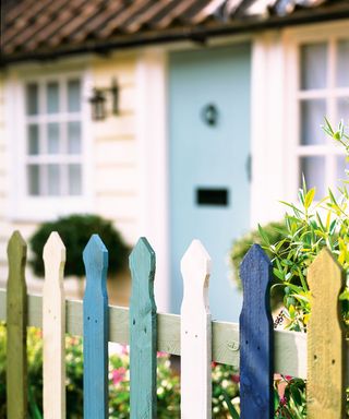 Fence decorating ideas featuring a picket fence painted in white, yellow, green and blues.