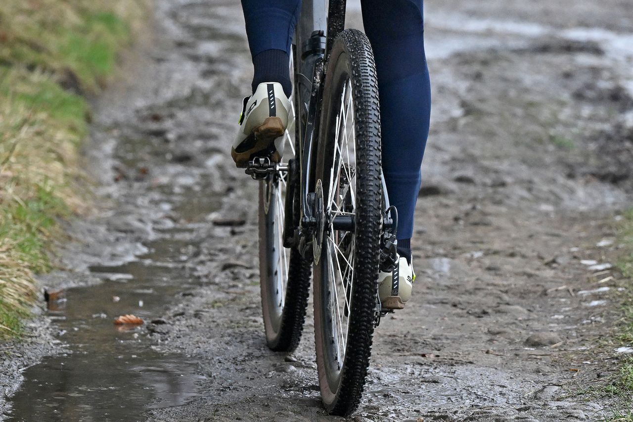 a bike with G-One RX Pro Gravel tyres riding away from the camera on a muddy trail