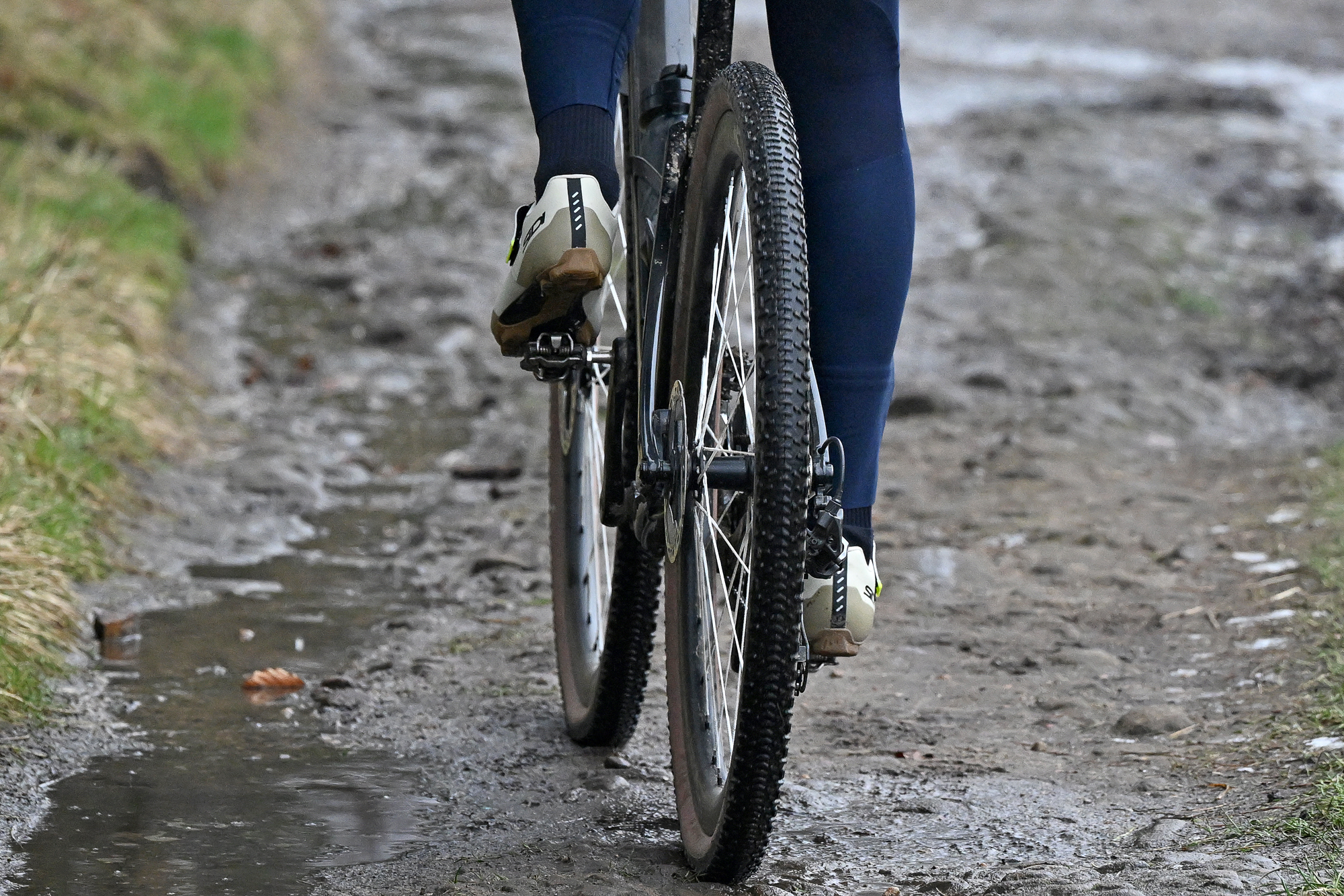 a bike with G-One RX Pro Gravel tyres riding away from the camera on a muddy trail