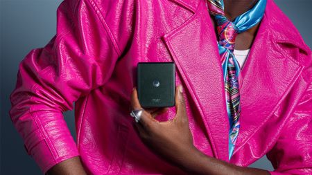 Close up of woman's upper body, wearing a pink jacket and holding a Motorola Razr handset