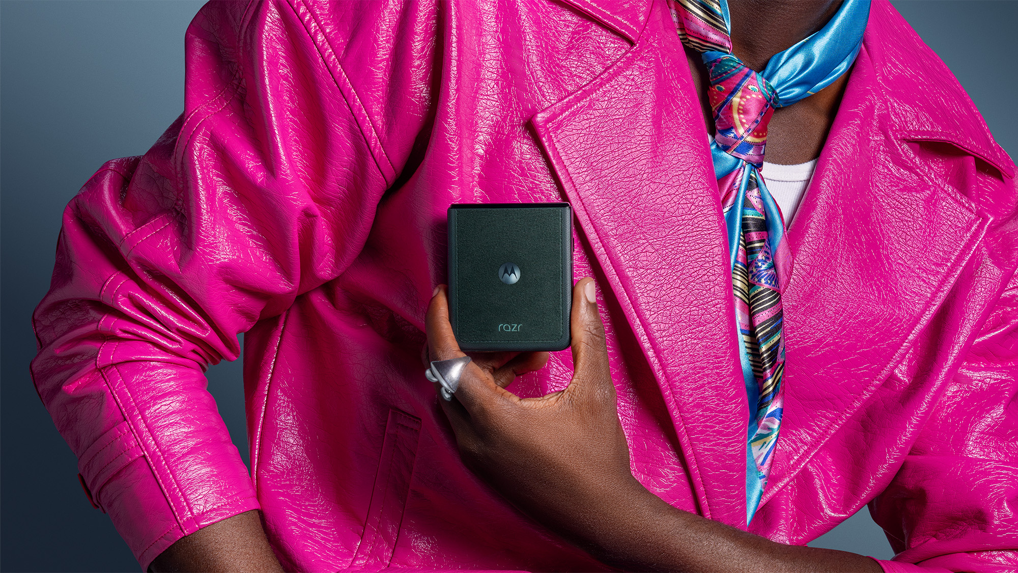 Close up of woman's upper body, wearing a pink jacket and holding a Motorola Razr handset