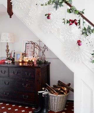 Christmas stair decor ideas with white banister, white paper snowflakes, ivy and red baubles