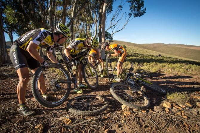 The Centurian Vaude Team assist the Yellow Jersey holders Topeak-Ergon Racing Team after they got a flat tyre during stage 5