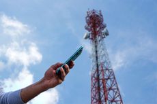 A person using a phone with a 5G mast in the background