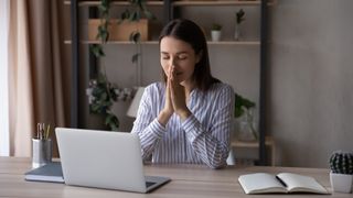 A woman looking relieved at her laptop in a modern office environment