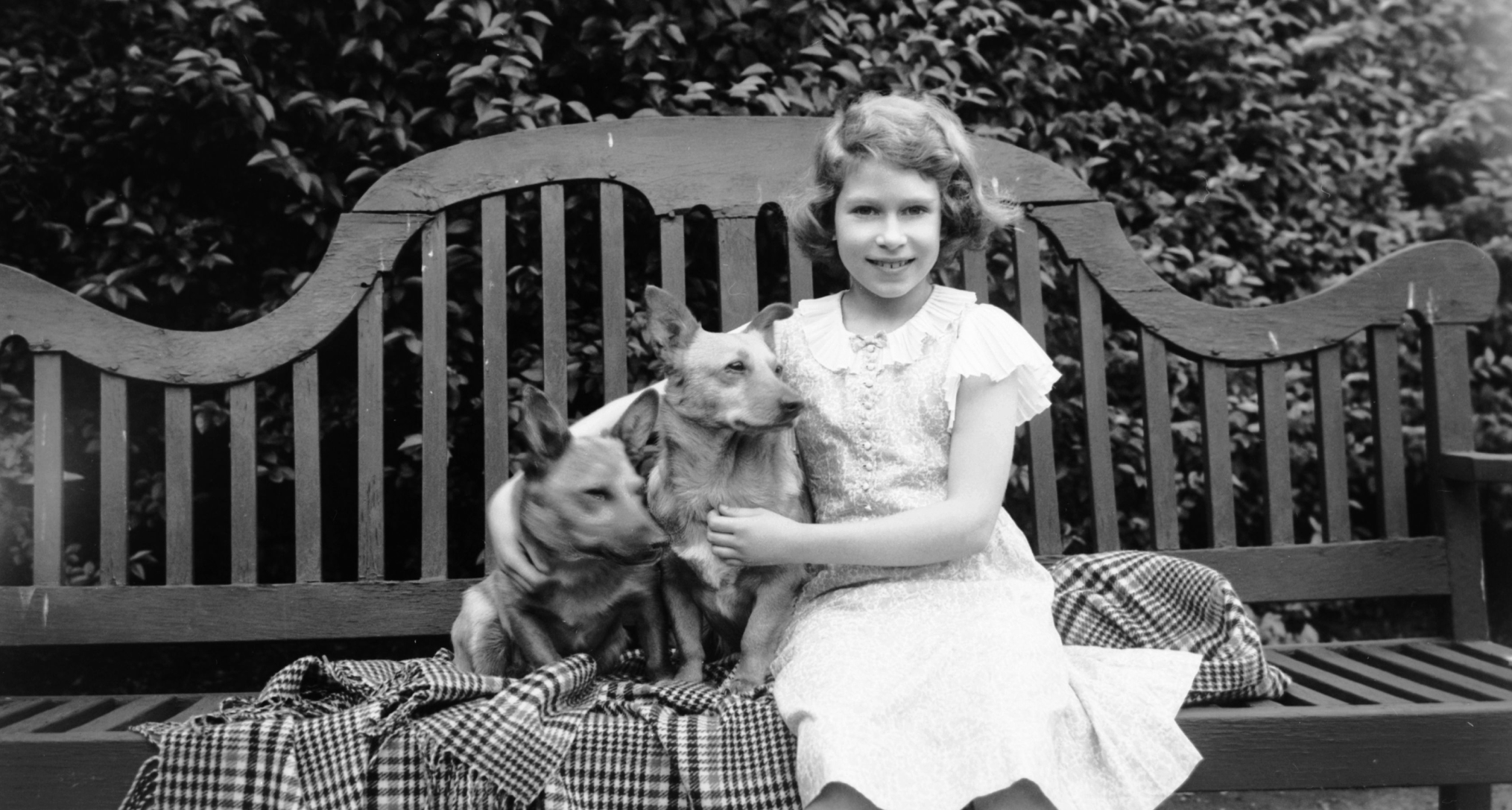  Queen Elizabeth as a child in 1936, sitting on a bench with a dog
