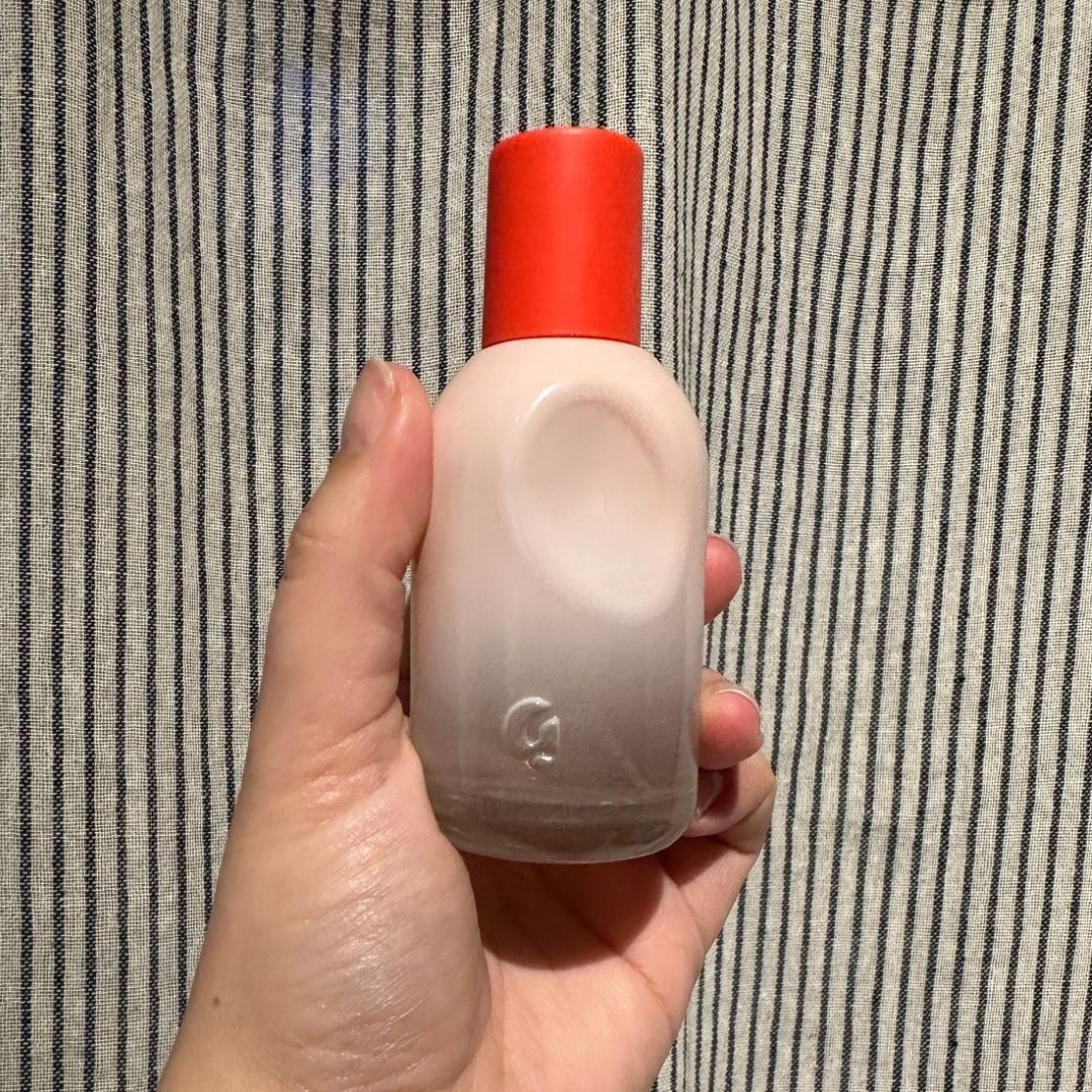 a picture of Rhiannon Derbyshire's hand holding a bottle of Glossier You perfume