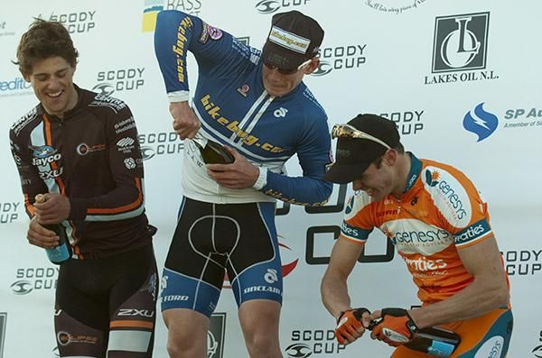 Stage two podium (l-r); Luke Davison (2nd,Jayco/2XU), Philip Grenfell (1st,Bikebug.com), and Steele Von Hoff (3rd,Genesys Wealth Advisers) struggle with the champagne.