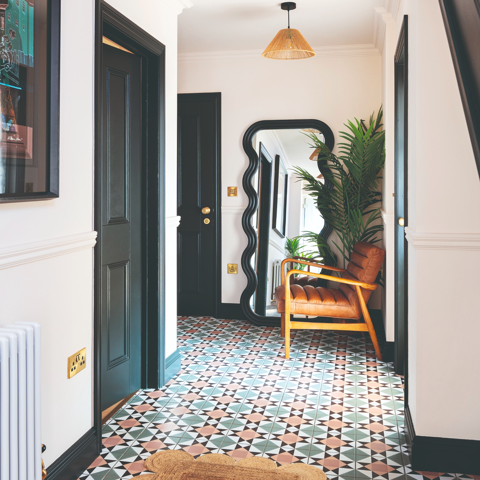A white hallway with black doors, a tiled patterned floor and a wavy full-length mirror