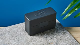 The DJI Mic Mini in black on a stone surface.