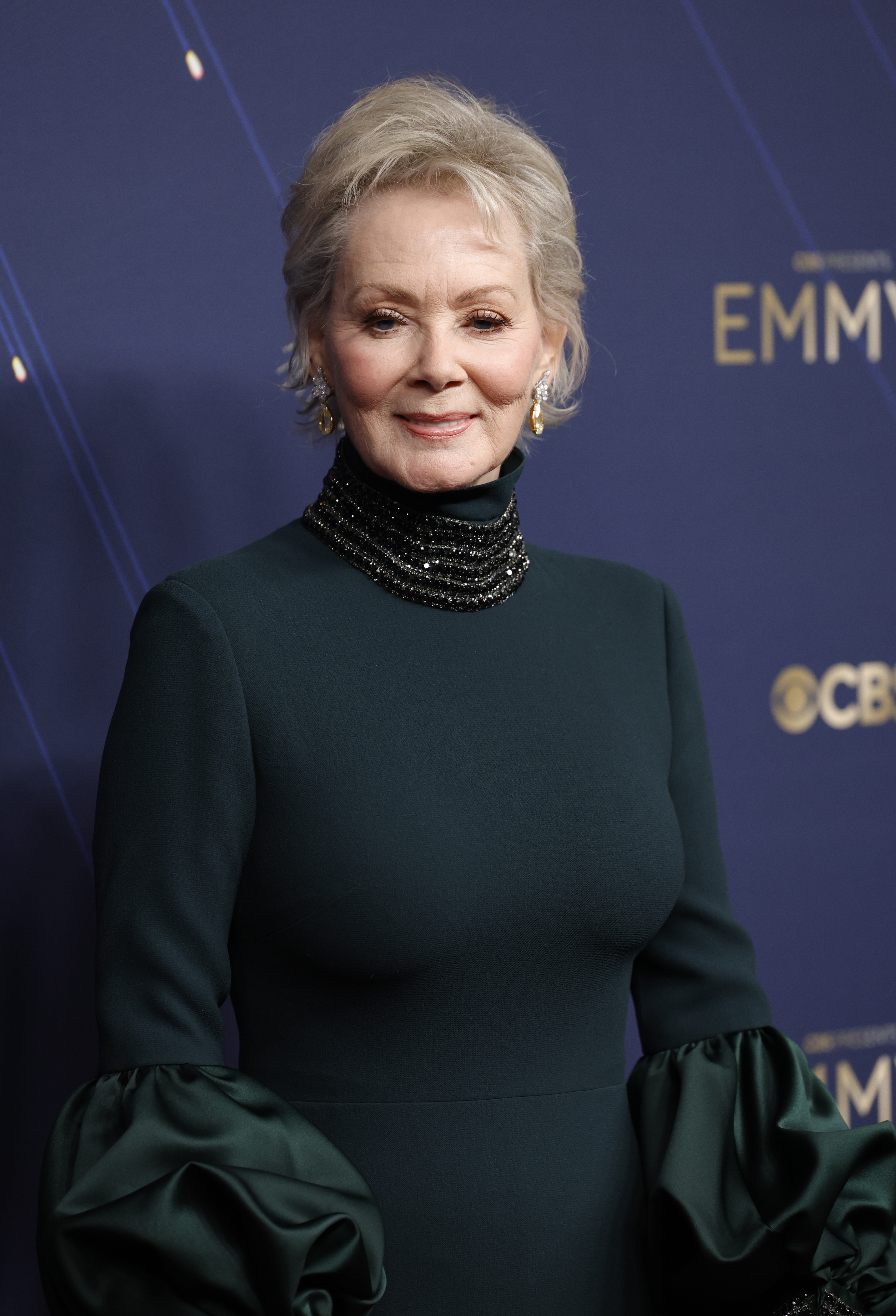 a woman with a gray bob and a dark emerald green dress