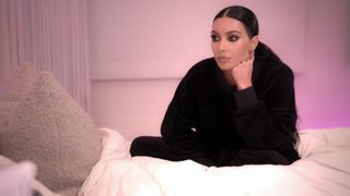Kim Kardashian sitting in bed in The Kardashians