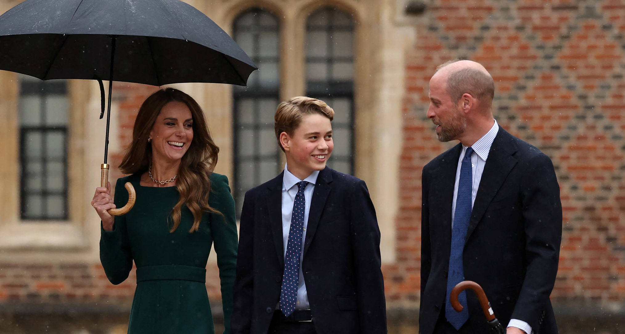 Princess Kate holding an umbrella, walking next to Prince George and Prince William