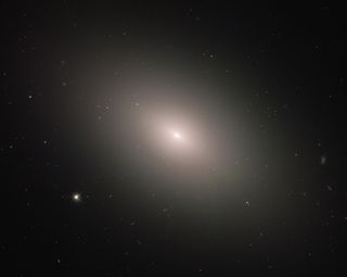 This brilliant and diffuse object glowing in deep space is the elliptical galaxy NGC 4621, also known as Messier 59. Located about 50 million light-years from Earth, it is one of the nearly 2,000 galaxies in the Virgo Cluster. The Hubble Space Telescope captured this new view of the galaxy using its Advanced Camera for Surveys.