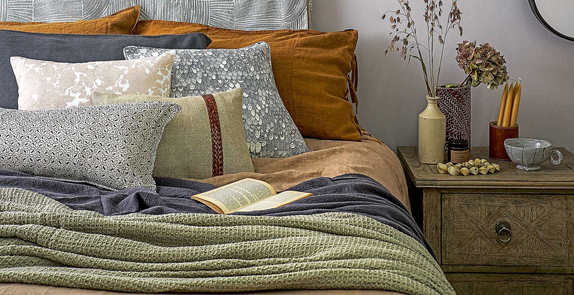 green bedroom with layers of blankets to show how to make a home cosy