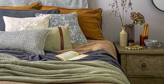 green bedroom with layers of blankets to show how to make a home cosy