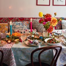 Table laid with colourful dishes of food, vase of flowers and lit candles. Festive table settings and cooked dishes at Christmas time, at Ravinder Bhogali's Mayfair restaurant, Jilkoni.