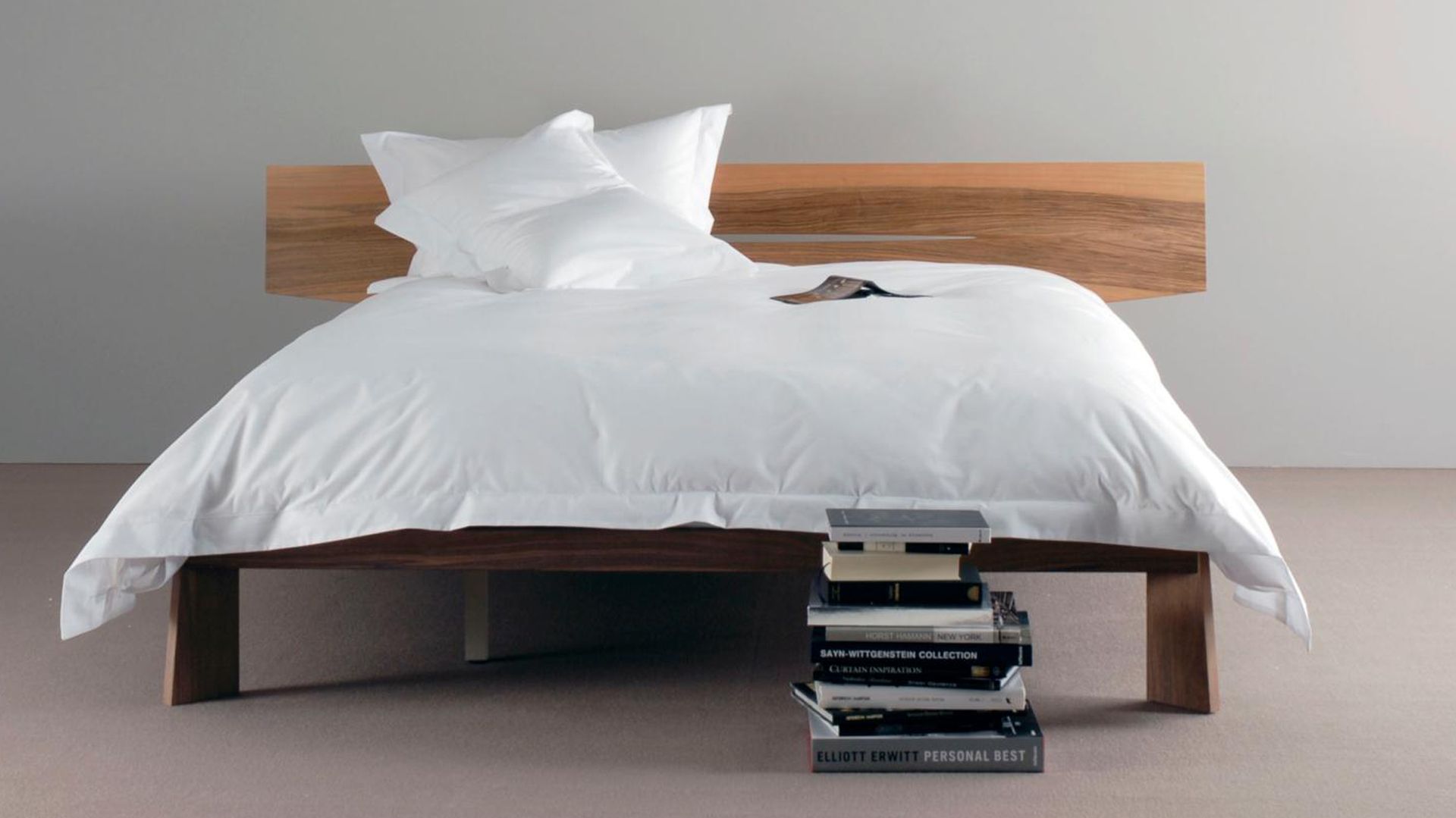 Wooden framed bed with white duvet cover looking freshly made to illustrate how to clean a mattress