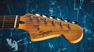 Squier Jazzmaster headstock on blue background