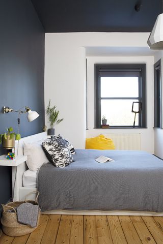 teenage boy's bedroom with black and white walls, grey bedding, exposed wood floors and plants