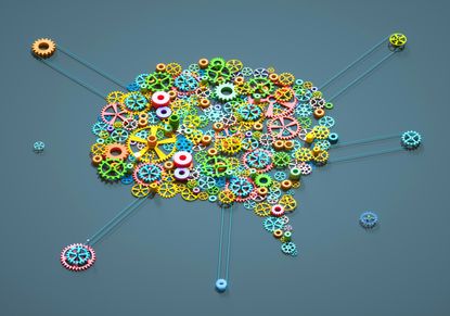 Digital generated image of multi coloured gear wheels connected together in shape of brain on grey background