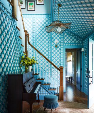 blue lattice style entryway with piano and wooden staircase