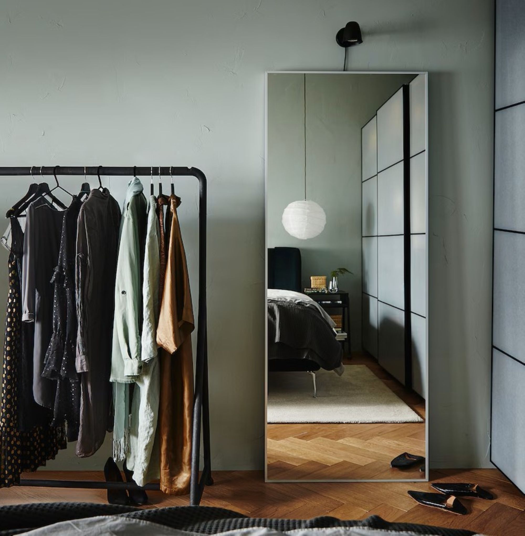 a room with a rolling rack and a large rectangular mirror