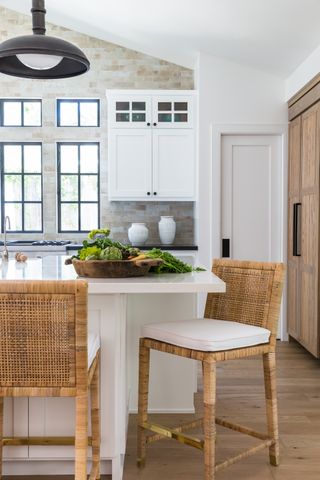 Kitchen with white and wood cabinets, white island, wood floor and natural tile backsplash