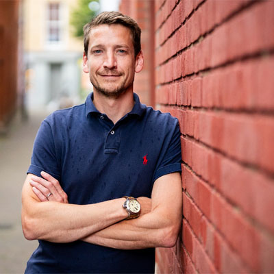 picture of Andy Simms a young man in a blue polo shirt with light brown hair