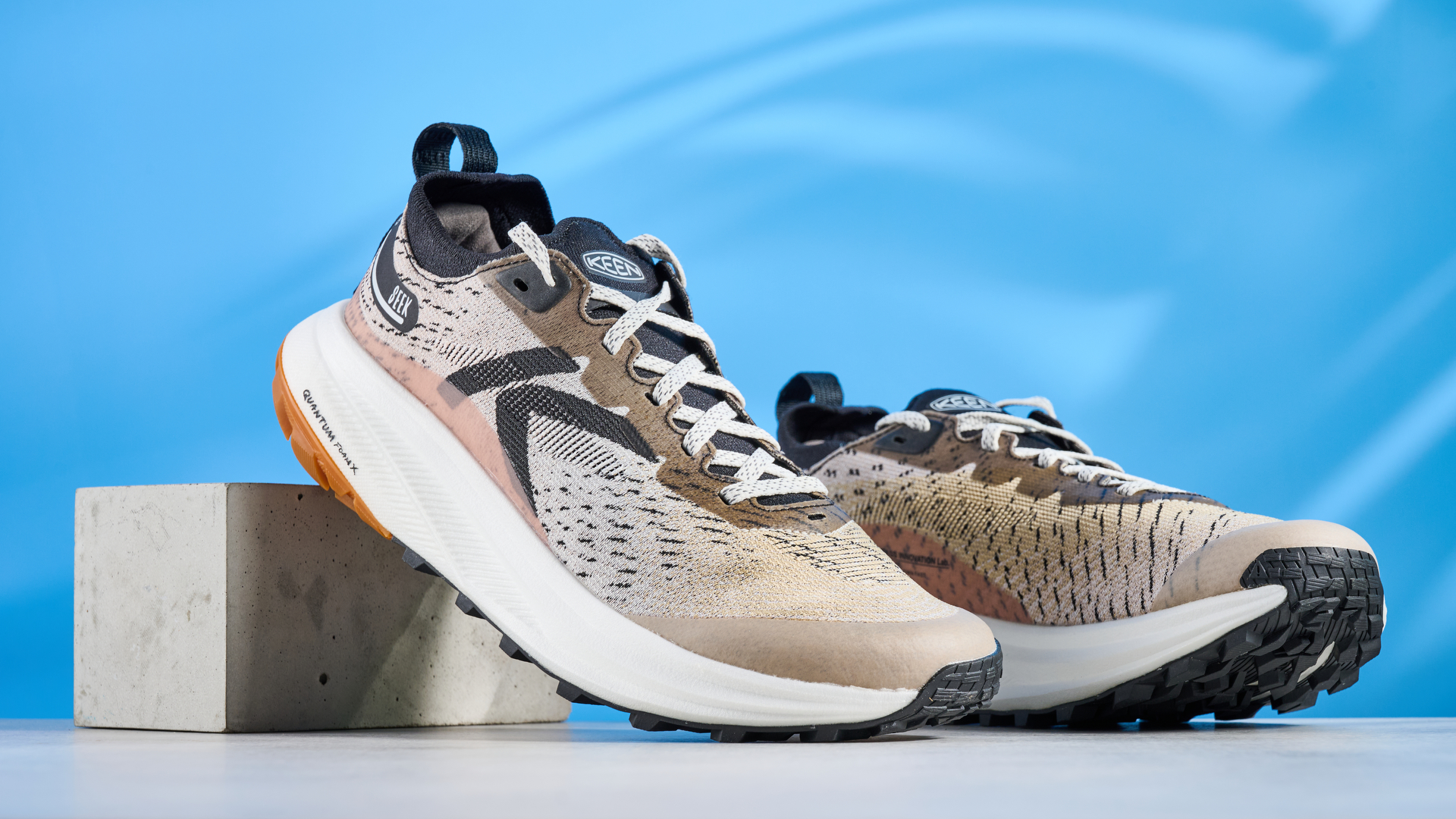 the keen seek trail shoes in brown, black, and beige photographed against the blue tom's guide background