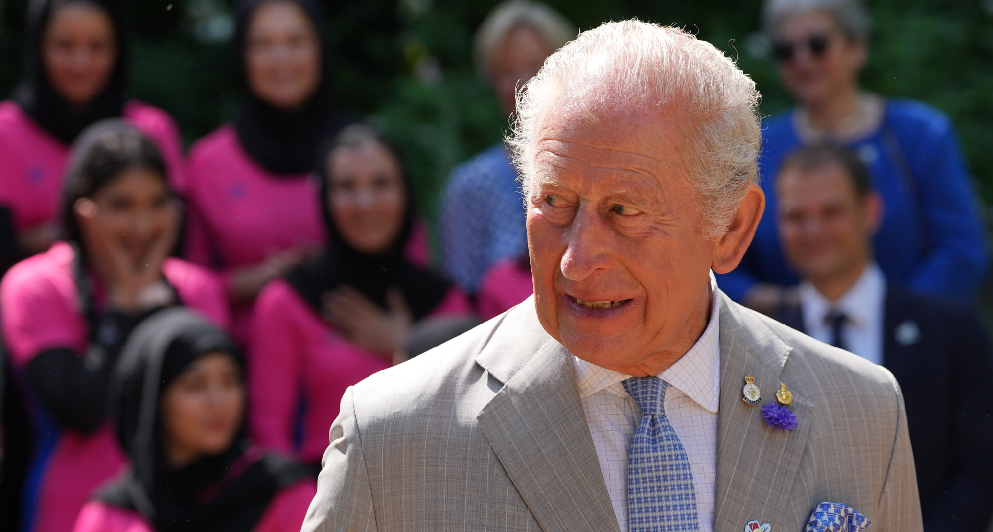 King Charles wearing a grey suit and smiling