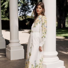 Model wearing a white longsleeve floral dress leaning against a column for the Forever New discount code page