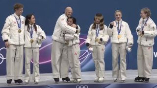 The 2026 Team USA Olympic Figure Skating team stands atop the Olympic podium after their gold medal win.