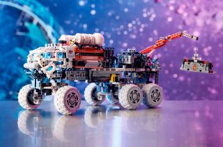 photo of a multicolored LEGO rover on a shiny table against a purple and blue cosmic-themed backdrop