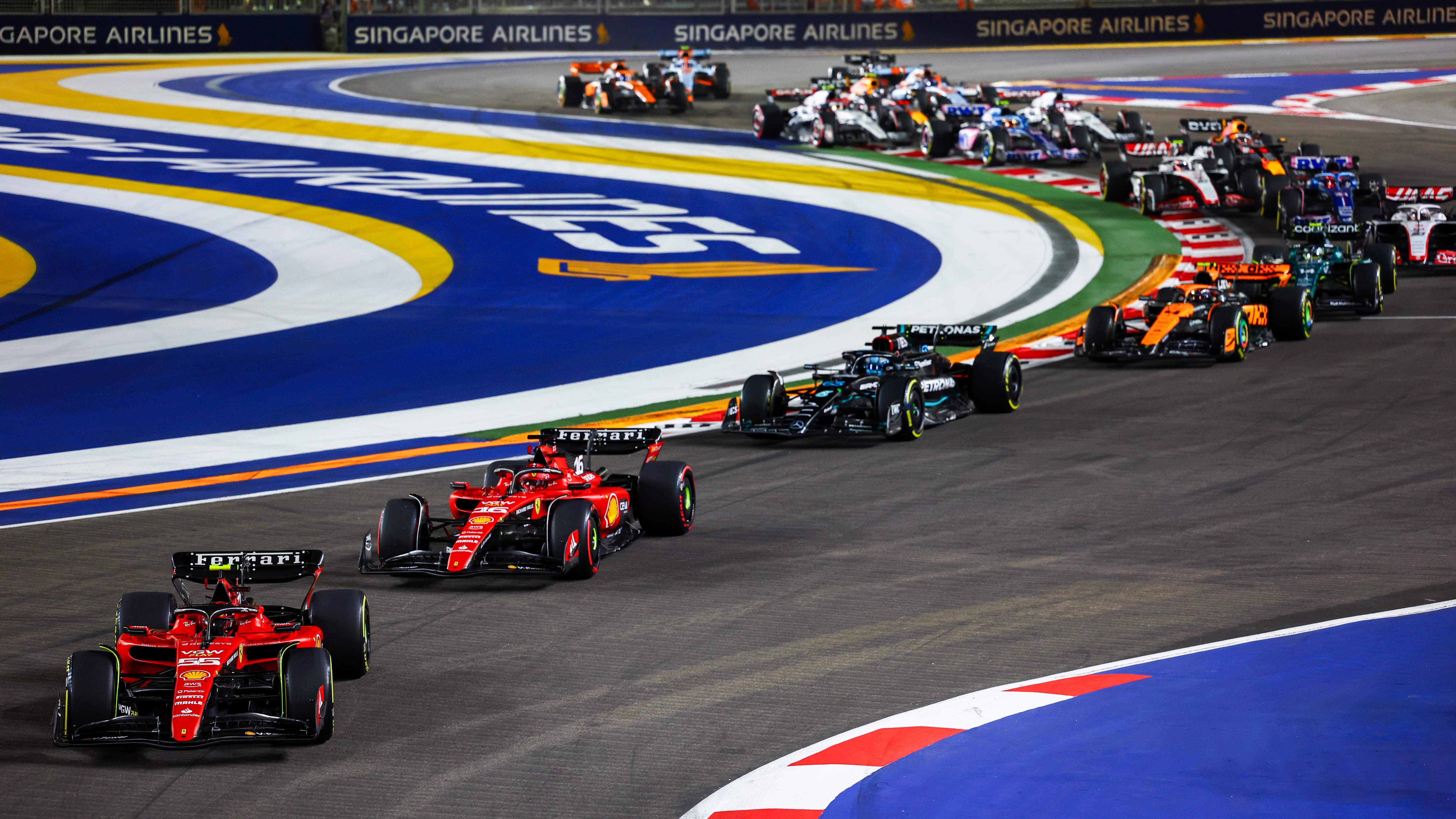 Carlos Sainz of Spain driving (55) the Ferrari SF-23 leads Charles Leclerc of Monaco driving the (16) Ferrari SF-23 and the rest of the field at the start during the F1 Grand Prix of Singapore at Marina Bay Street Circuit on September 17, 2023 in Singapore, Singapore. 